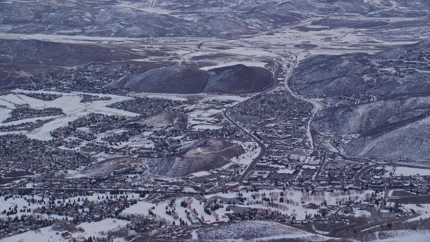Aerial panorama of an urban city covered in snow and mountains nearby