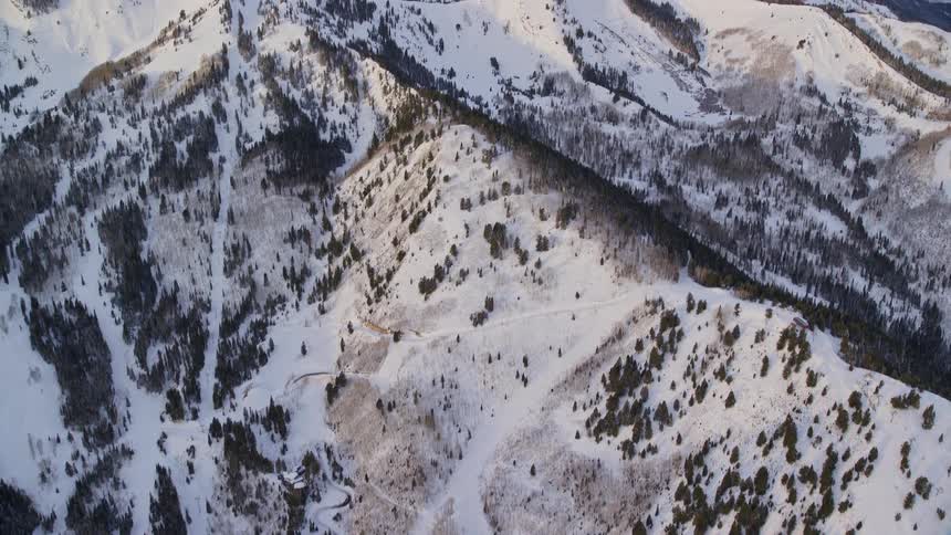 An aerial view of a snowy region where there are several streets and high mountains