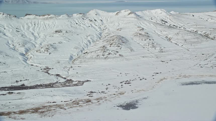 Aerial view of snow covered field and mountains