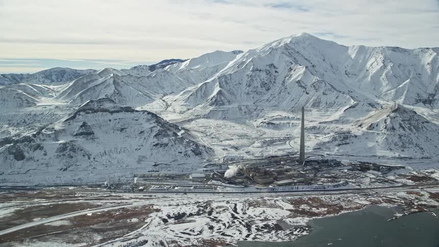 Obelisk towers over snow covered coastal town bordering mountains on a cloudy winter day