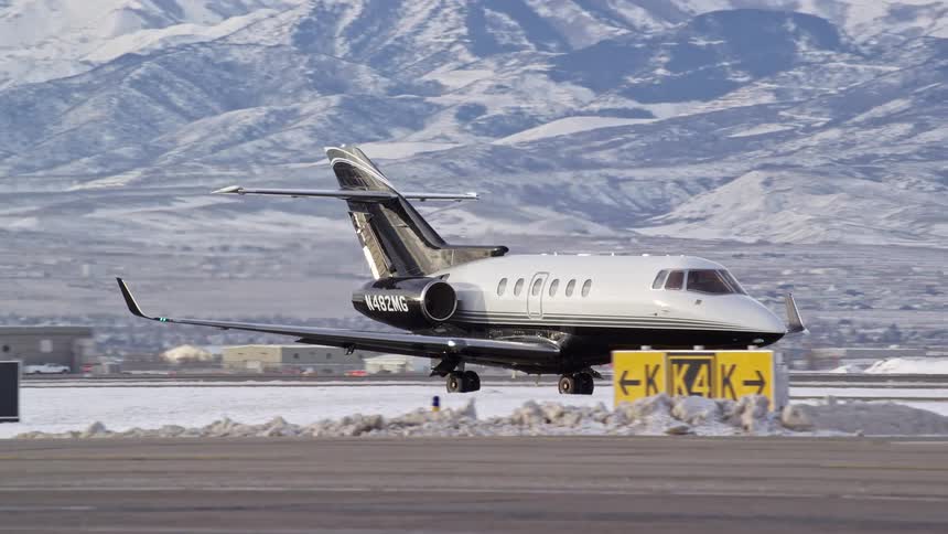 Airplane moves along the runway with snowy mountains in the background