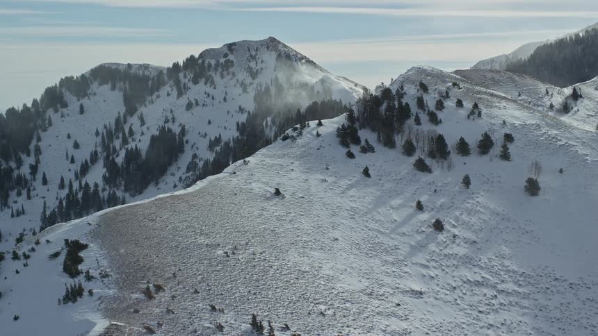 Aerial of snow covered mountain peak during sunny morning