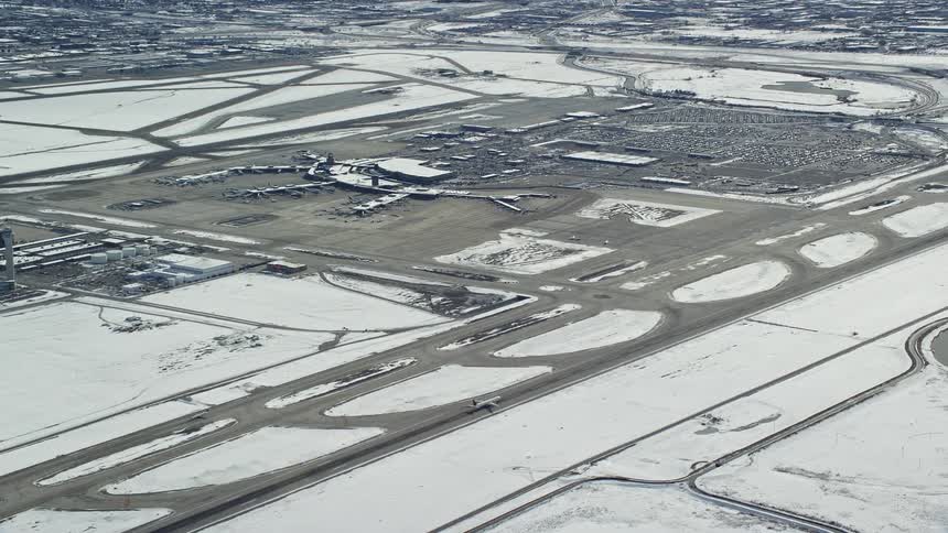 An airplane is preparing to take off on a runway and the surrounding area has snow on the ground