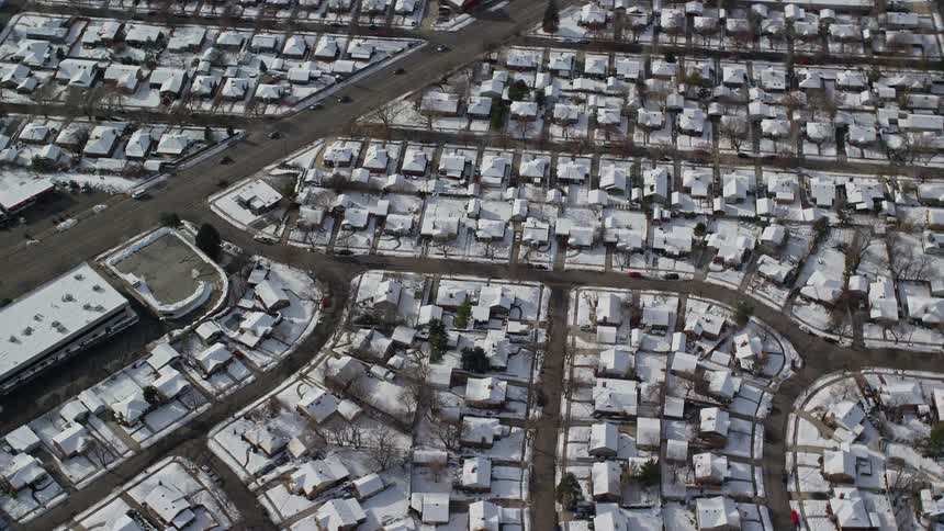 An aerial view of a city with many houses and the weather is cold with a lot of snow