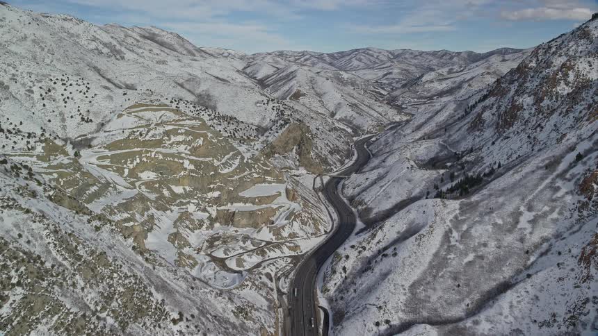 A large road in a valley in the middle of huge snow mountains