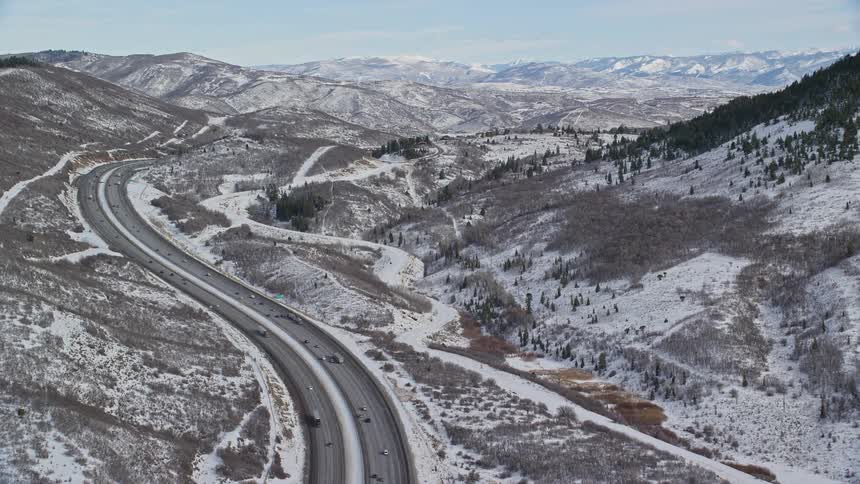 A highway with cars driving next to snowy mountains