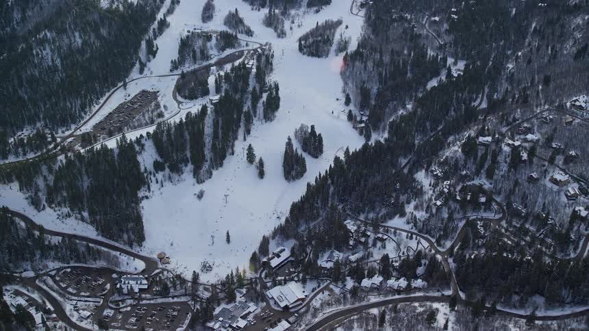 Aerial panorama of a village next to mountains with snowcovered conifers