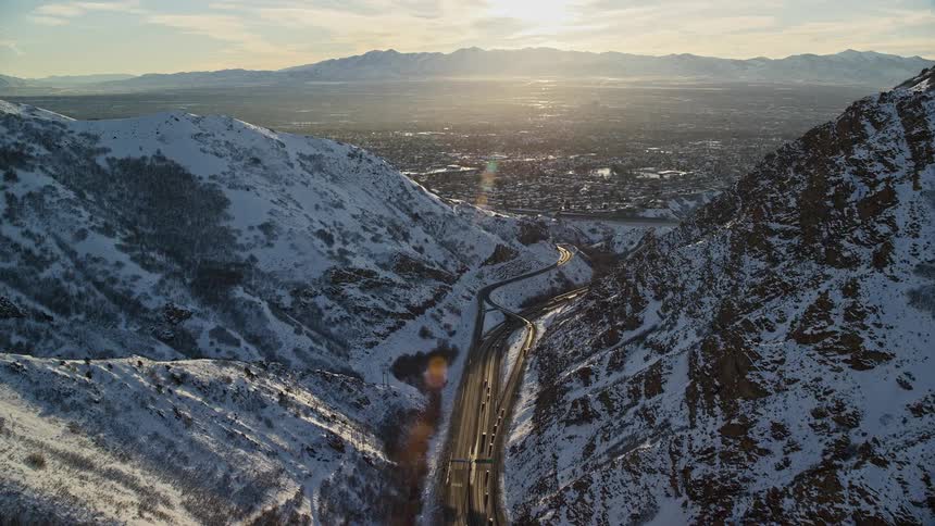 Aerial view of a highway throu the mountains leading to a city