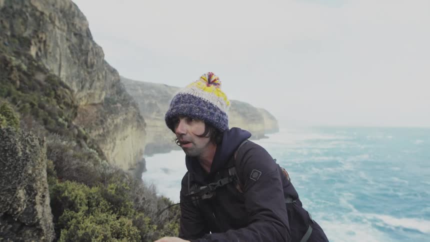 A man on top of a mountain with his back to the sea