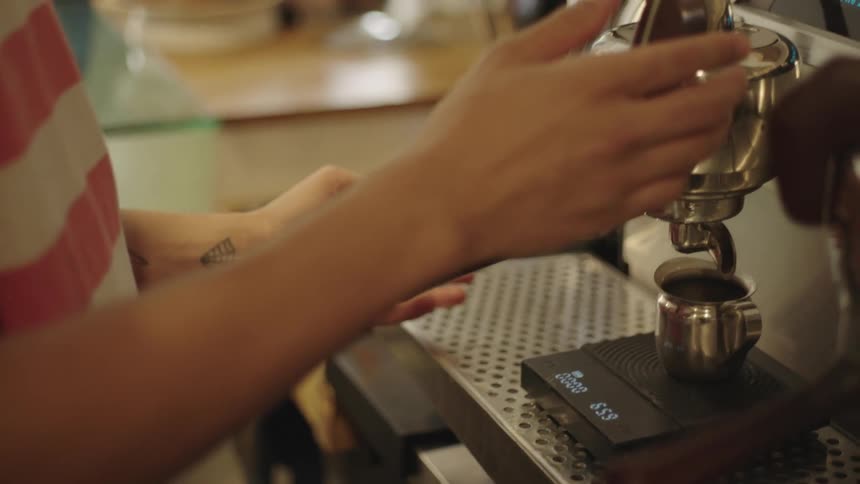 Barista operates espresso machine while others work in the background