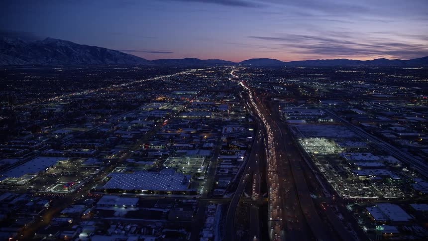 Aerial panorama of an urban city at night with cars moving along the roads