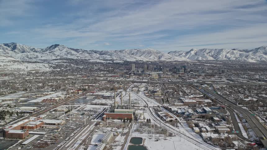 Aerial view of an urban city with a factory surrounded by a chain of snowcovered mountains
