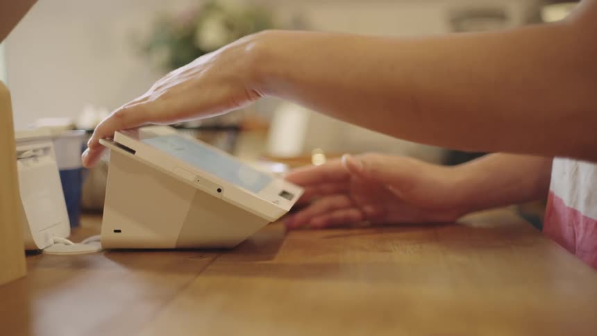 A person using a touchscreen technology payment device on a table