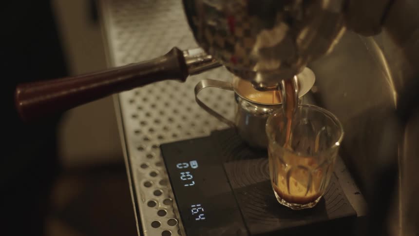 Glass cup receiving espresso shot from a machine