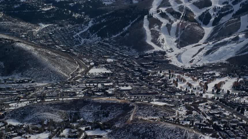 Several buildings are located in a valley between snow covered mountains