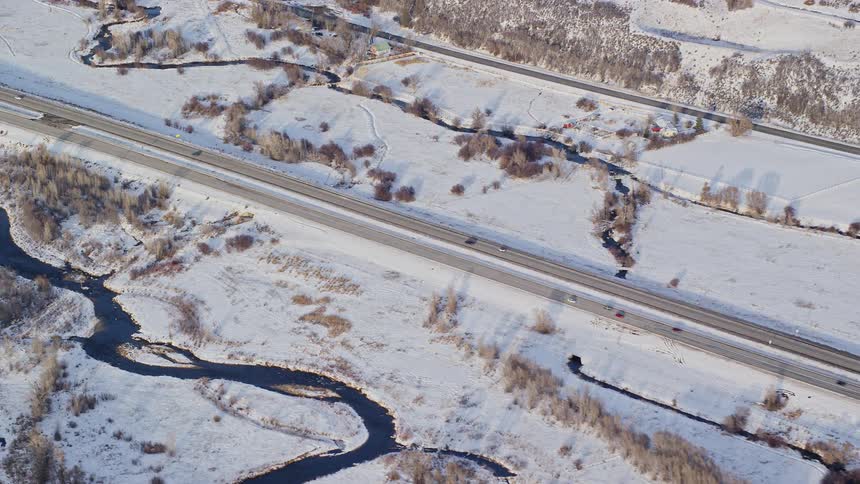 Aerial view of a road through a snowcovered landscape with a flowing river beside it