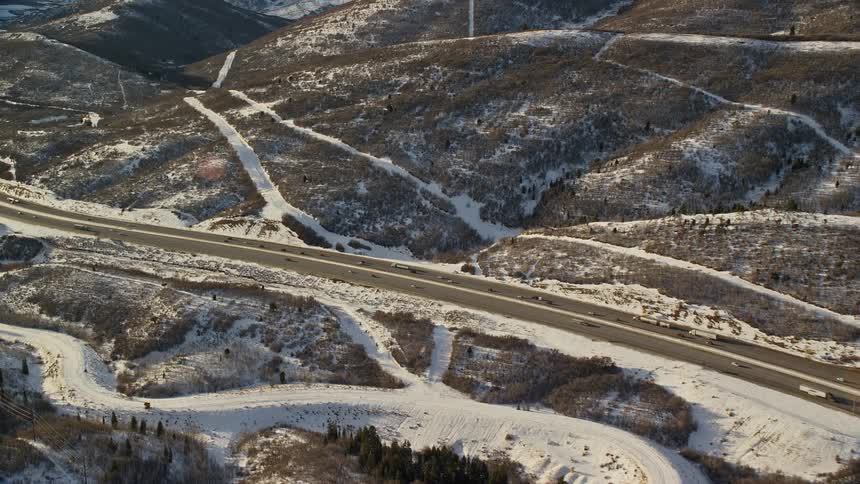Aerial panorama of a snowcovered mountain with a road and vehicles passing by