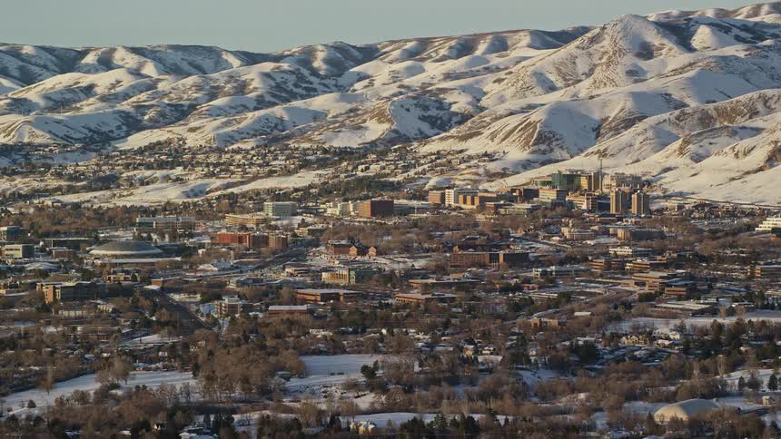 Panorama of houses and an urban city surrounded by snowcovered mountains on a morning