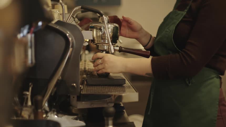 A person is making coffee using a coffee maker and some metal utensils