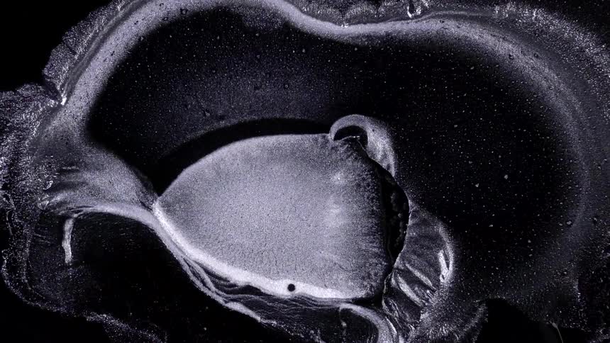 Expanding silver inks moving over black background