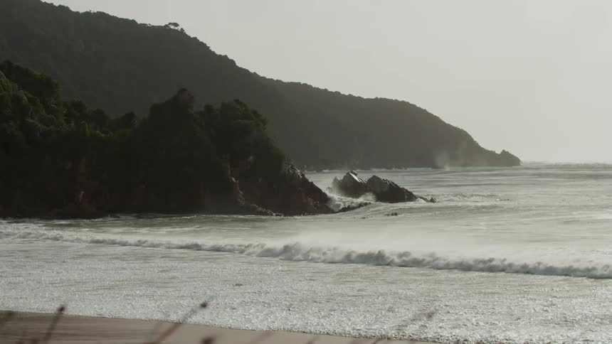 Gentle waves break on the beach shore with mountains