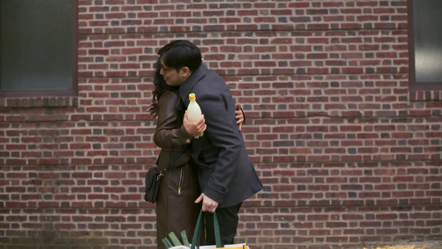 Man and woman meeting on the street greeting with a hug and then walking together in the same direction