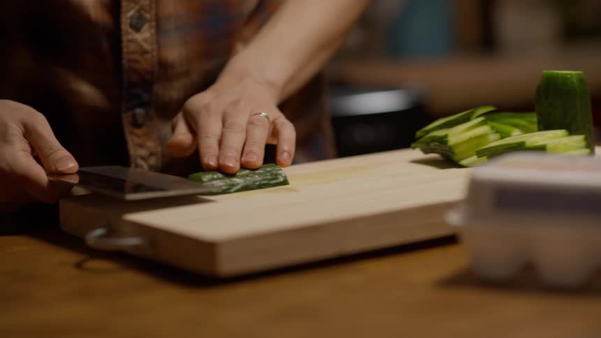 A person cutting vegetables on a wooden cutting board