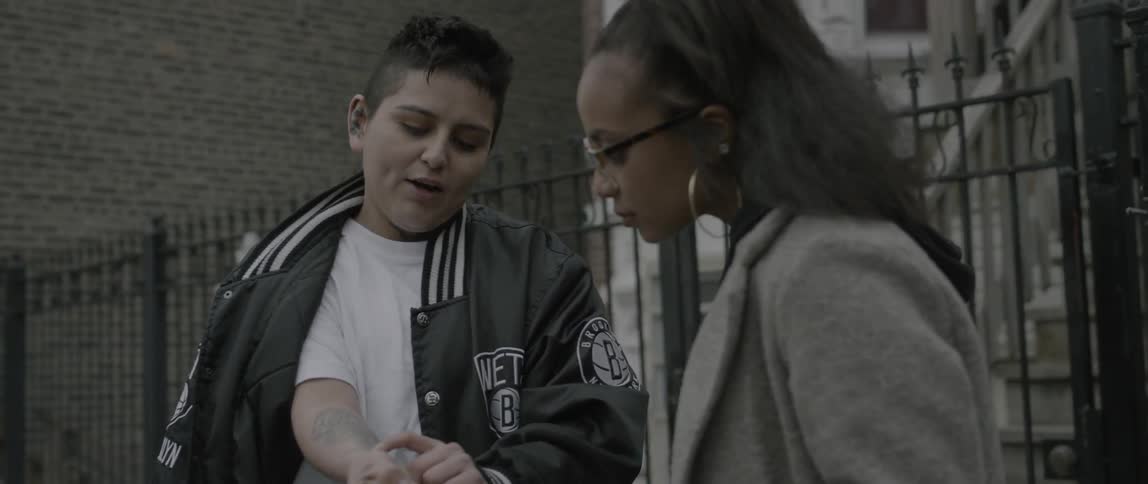 A woman shows another woman the tattoos on her arms