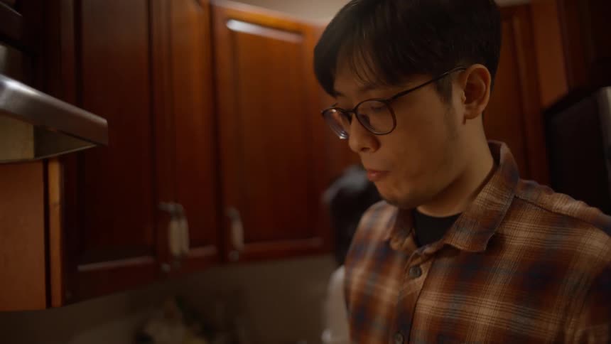 A man in the kitchen trying food