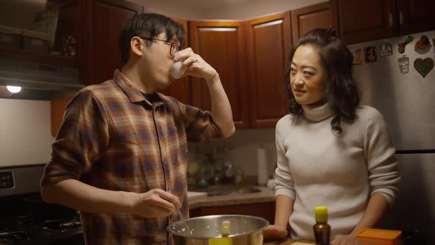 Man and woman preparing food in the kitchen the man tastes a bit to check the flavor