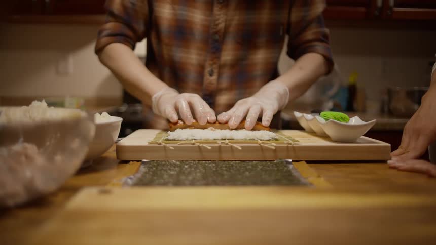 Closeup of a mans hands with gloves putting protein on rice