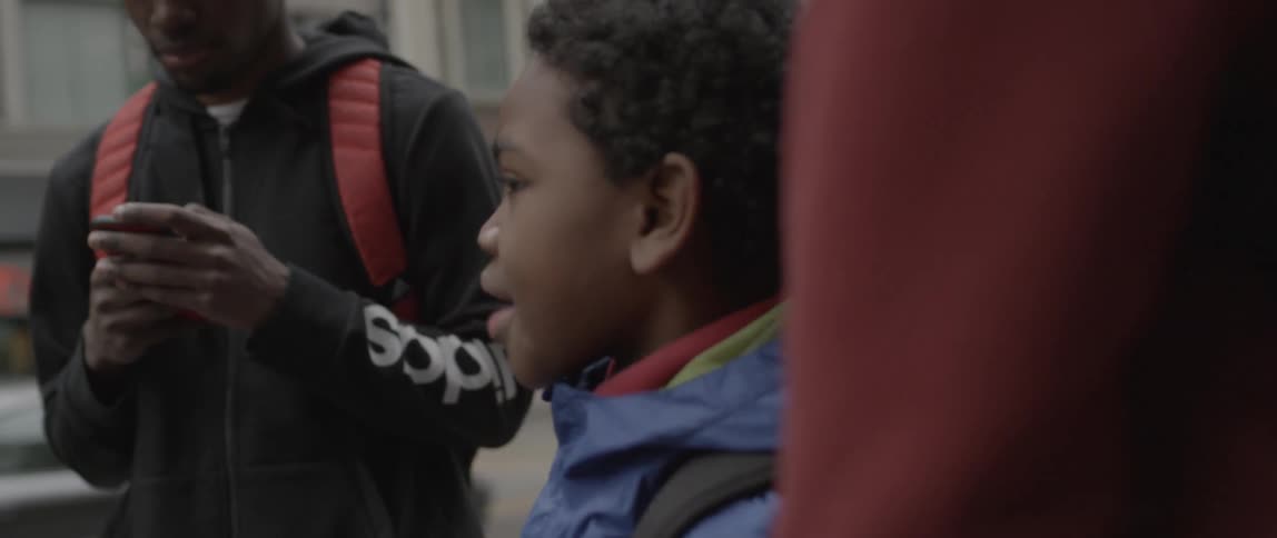 A child talks to two people around him laughing