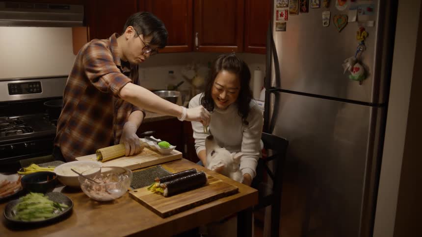 A man feeds his dog some of the food he is cooking