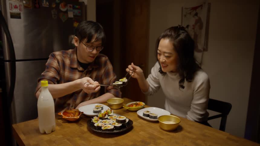 Asian man and a woman enjoying sushi at the kitchen table