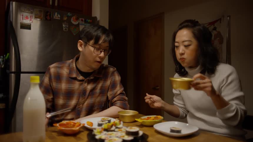 Couple sitting at the table at night eating asian food