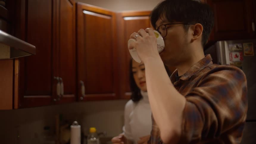 Couple cooking in kitchen and man drinks tea