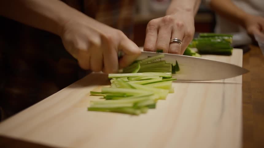 A man is cutting up vegetables on a cutting board
