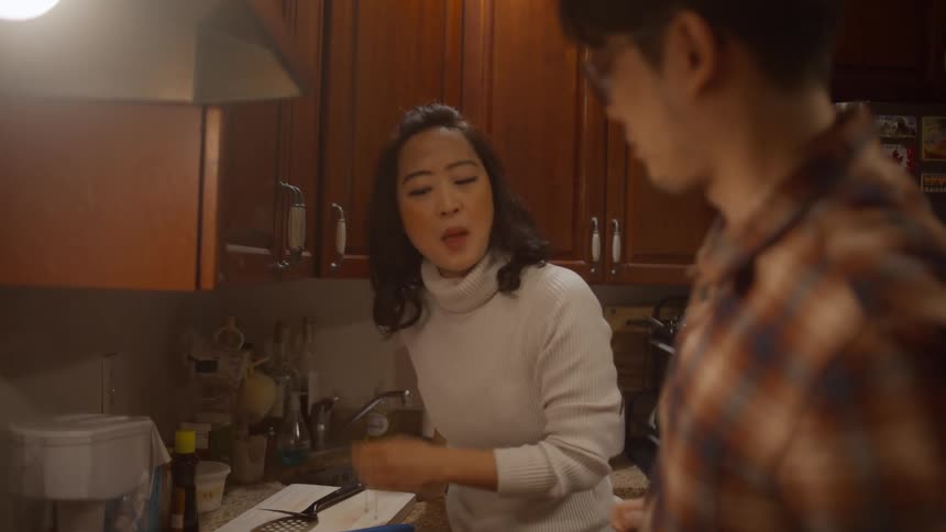 Couple in the kitchen cooking and the husband spooning food into his wifes mouth to taste