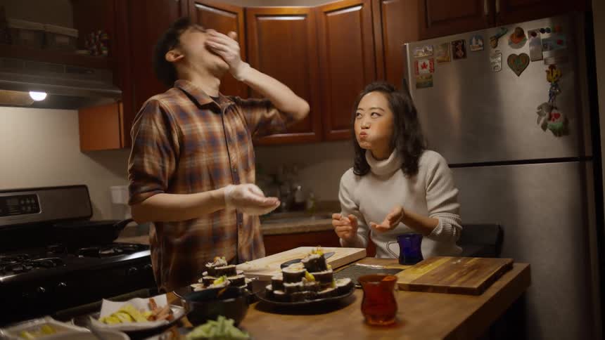 Couple in the kitchen eating while cooking