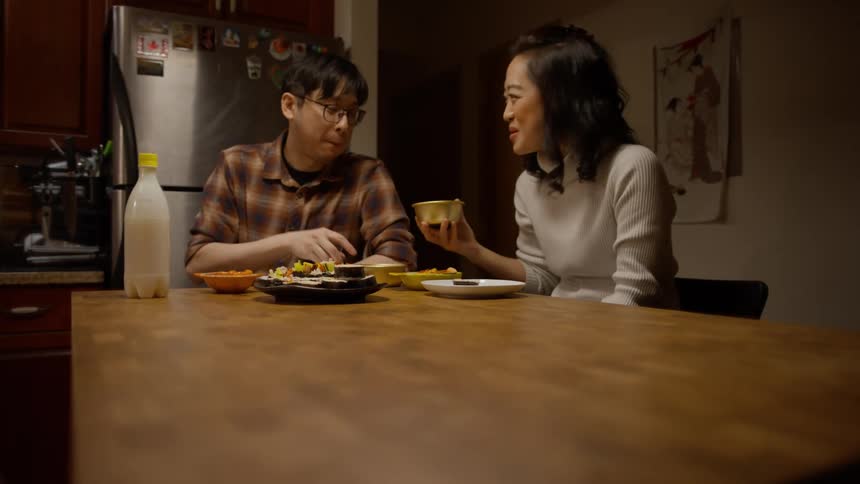 A couple eating dinner at the kitchen table while talking