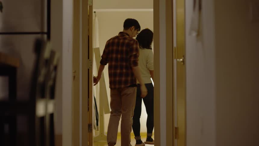 A man and a woman head to the bedroom followed by their dog and they close the door behind them