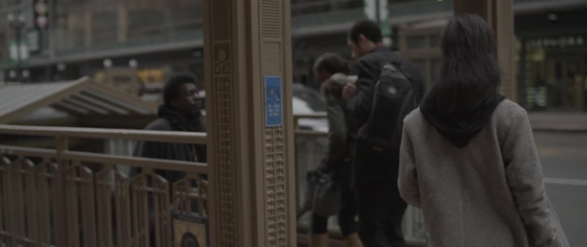 A woman walks over to and down the subway stairs