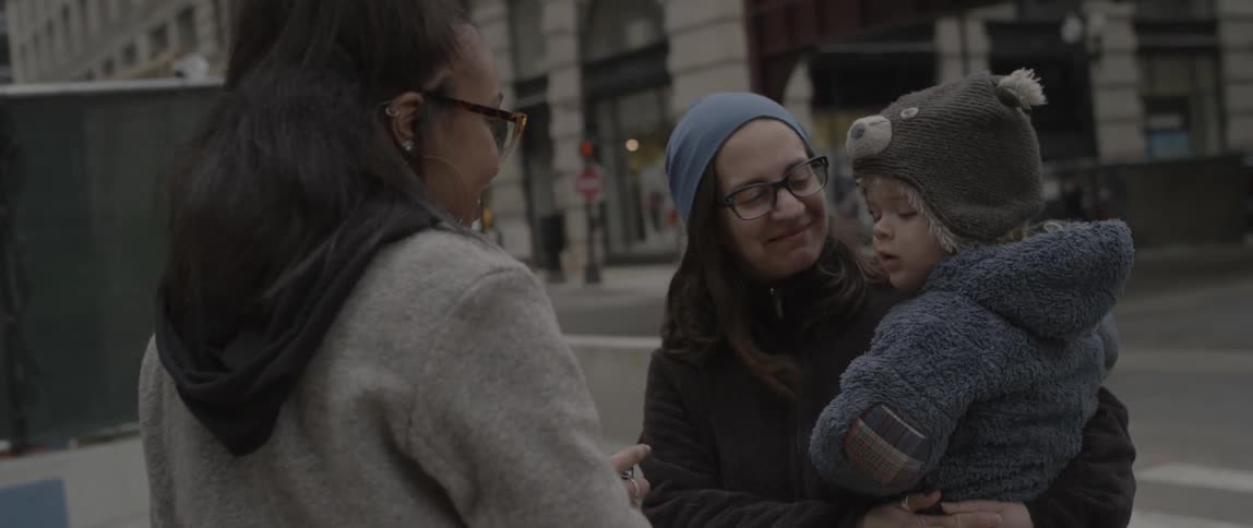 Two women chat on a city sidewalk