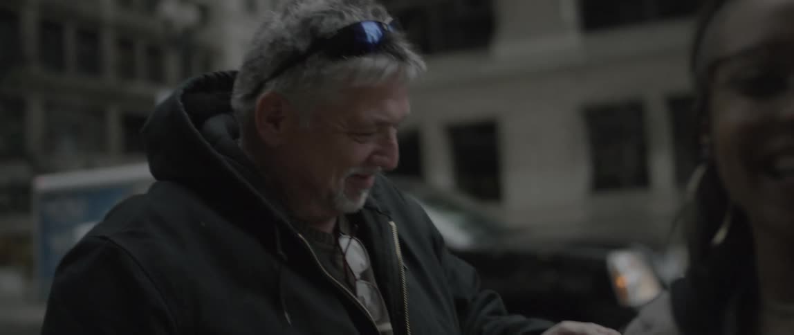 A woman hands a man a photograph and hugs him