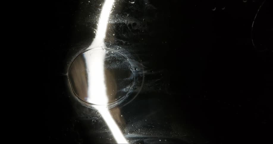 Light shines on a black sphere as it passes through a large dark orb