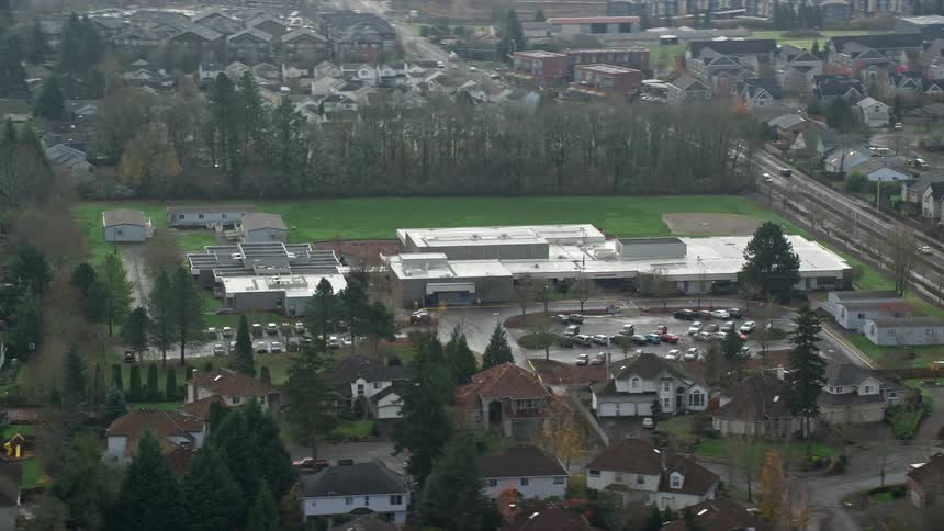 Aerial of a high school in the middle of a suburban neighborhood on a hazy day