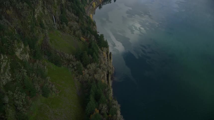 Aerial of rocky mountain with waterfall falling into the sea