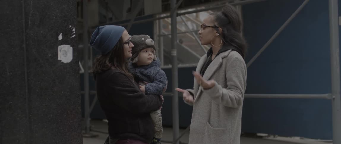 A woman talks with another woman carrying a child