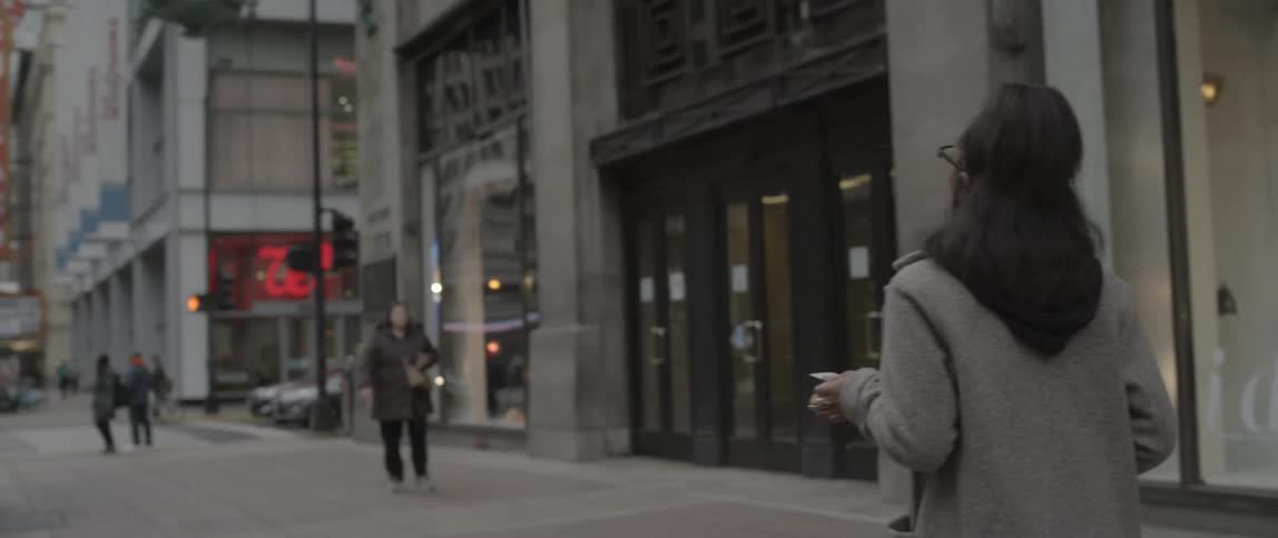 A woman looks at a card then walks down the street