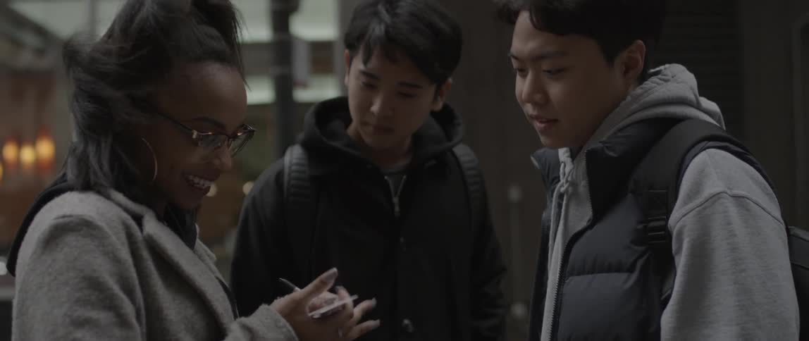 A woman writes on something and hands it to a man before giving them a hug